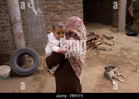 A local mother holds her youngest child in Bairat, a village on the West Bank of Luxor, Nile Valley, Egypt. Stock Photo