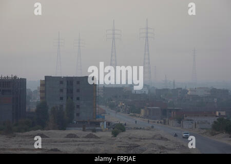 Looking east from the West bank of the river Nile, of electricity power pylons and local housing in the modern city of Luxor, Nile Valley, Egypt. Stock Photo