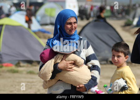 Idomeni, Greece, 22 March 2016. A woman holding a baby cries  at a makeshift camp for refugees and migrants at the Greek-Macedonian border, near the village of Idomeni. Credit:  Orhan Tsolak / Alamy Live News Stock Photo