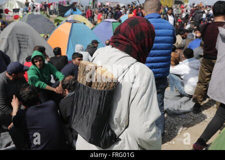 Idomeni, Greece, 22 March 2016. A woman walks carrying a rucksack filled with two pices of firewood during an 'Open the Borders' sit-in protest on the railway trucks at a makeshift camp for refugees and migrants at the Greek-Macedonian border, near the village of Idomeni. Credit:  Orhan Tsolak / Alamy Live News Stock Photo