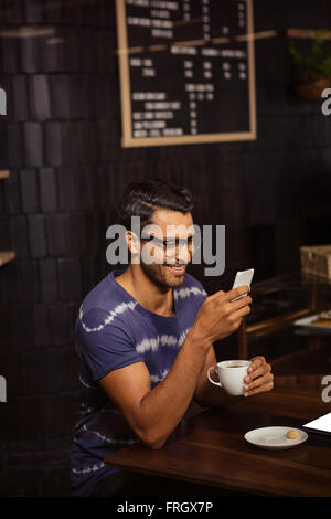 Man using his smartphone and drinking coffee Stock Photo