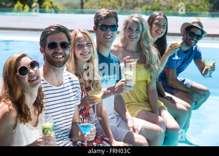 Happy friends sitting in swimming pool Stock Photo