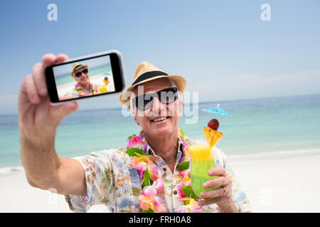 Senior man holding a cocktail glass and taking a selfie Stock Photo