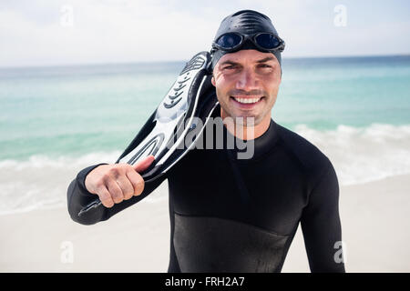 Portrait of surfer with flippers standing on the beach Stock Photo