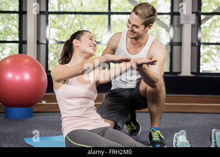 Trainer motivating a woman while doing crunches Stock Photo