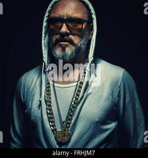 Portrait of an older street gangster, middle aged man wearing tracksuit and golden jewelry. Stock Photo