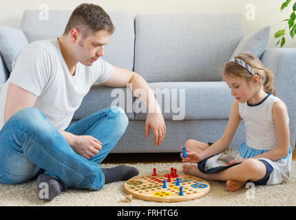 Little girl and her father playing ludo. Stock Photo