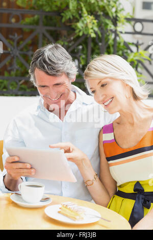 Happy woman pointing at tablet to man Stock Photo
