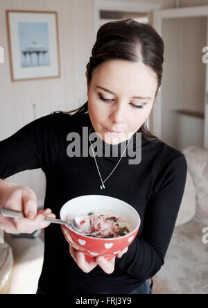 Young woman in her 20s eating healthy bowl of porridge for breakfast Stock Photo