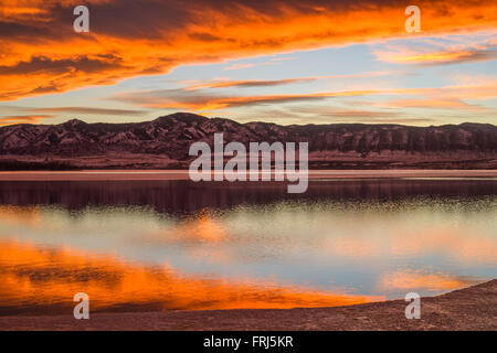 Sunset Spring Mountain Lake - Colorful stormy clouds rolling over a melting ice lake, with snow mountain range reflection. Stock Photo