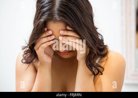Unhappy woman standing in bathroom Stock Photo