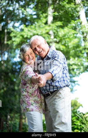 Portrait of senior couple dancing against trees Stock Photo