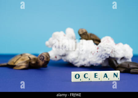 Wooden turtle figurines with coral on blue background Stock Photo