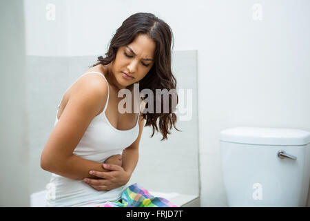 Young woman having stomach pain in bathroom Stock Photo