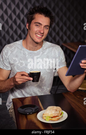 Hipster man using tablet with coffee and sandwich Stock Photo