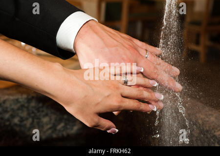 Hands of bride and groom with rings and water Stock Photo