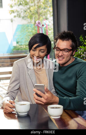 Couple using smartphone while drinking coffee Stock Photo