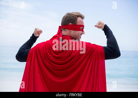 Man in superhero costume standing at sea shore Stock Photo