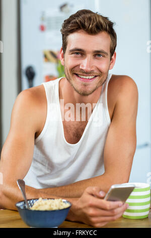 Handsome young man using mobile phone at breakfast table Stock Photo
