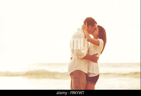 Happy romantic couple on the beach at sunset. Young lovers on vacation. Stock Photo