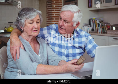 Senior man consoling wife holding pills container Stock Photo