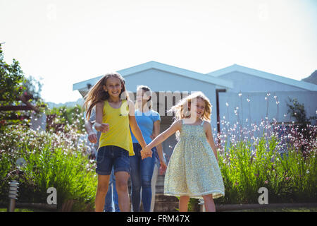 Happy sisters with parents walking behind against house Stock Photo