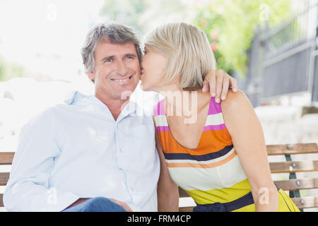 Blonde hair woman kissing man in park Stock Photo
