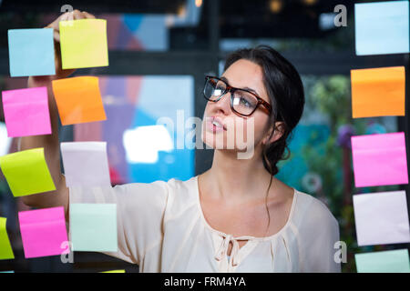 Businesswoman writing on sticky note Stock Photo