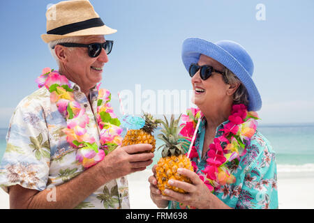 Happy senior couple wearing a garland and holding pineapple cocktail Stock Photo