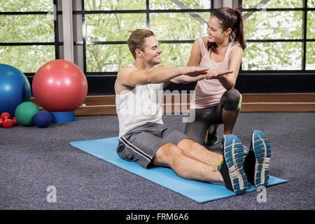 Trainer motivating a man while doing crunches Stock Photo
