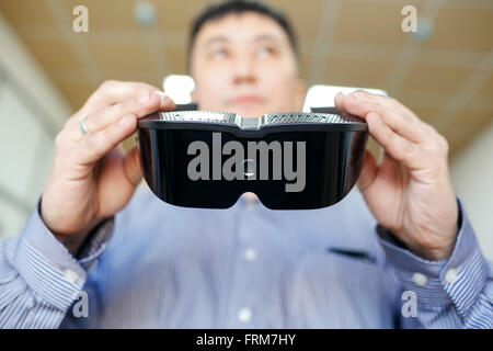 Virtual reality headset close up in hands of man who is going to wear them,  vr future concept and new technologies. Stock Photo