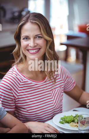 Smiling woman sitting at dining table Stock Photo