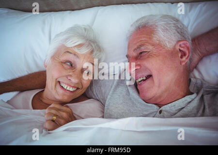 Laughing senior couple lying on bed Stock Photo