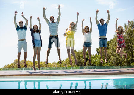 Happy friends jumping near swimming pool Stock Photo