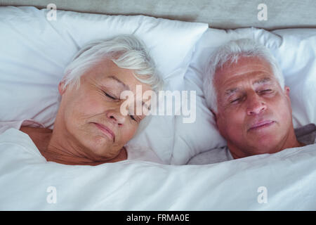 Senior couple sleeping on bed in room Stock Photo