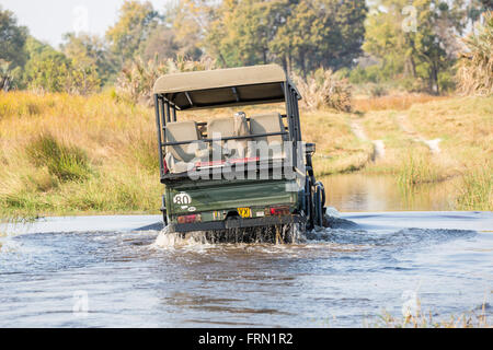Safari 4wd jeep crossing a river ford, Sandibe Camp, by the Moremi Game Reserve, Okavango Delta, Botswana, southern Africa Stock Photo
