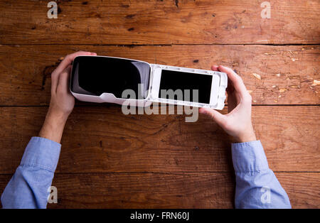 Hands of man holding virtual reality goggles and smartphone Stock Photo