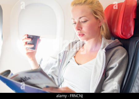 Woman reading magazine on airplane. Stock Photo