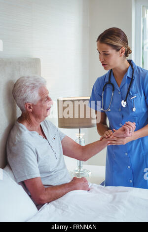 Nurse talking to senior man while examining Stock Photo