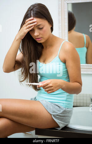 Worried woman looking at pregnancy test Stock Photo