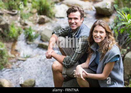 Portrait of hikers sitting on rock by stream Stock Photo