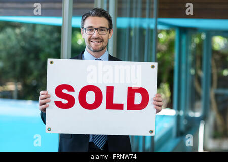 Real estate agent holding sold sign Stock Photo