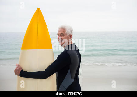 Happy senior man in wetsuit holding a surfboard Stock Photo