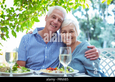 Happy retired couple with arm around at table Stock Photo