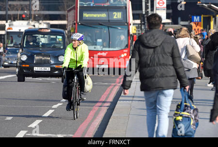 London, England, UK. Woman in hi-vis jacket and helmet cycling across Westminster Bridge Stock Photo