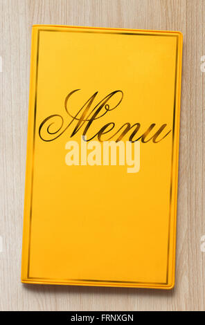 Yellow framed menu book on wooden background in closeup Stock Photo