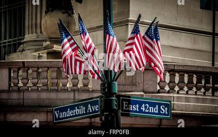 East 42nd St sign and group of American flags on lamppost, New York City, USA. Stock Photo