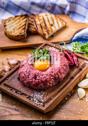 Raw beef .Tasty Steak tartare. Classic steak tartare on wooden board. Ingredients: Raw beef meat salt pepper egg garlic chili Stock Photo