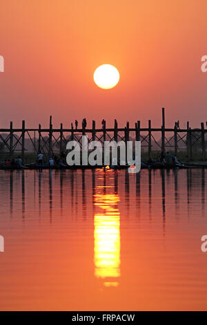 People crossing the U Bein Bridge across the Taungthaman Lake at sunset ...
