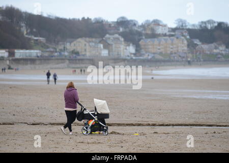 A woman on the beach with her pushchair, Hunmanby Gap near Filey, North Yorkshire, UK. Stock Photo